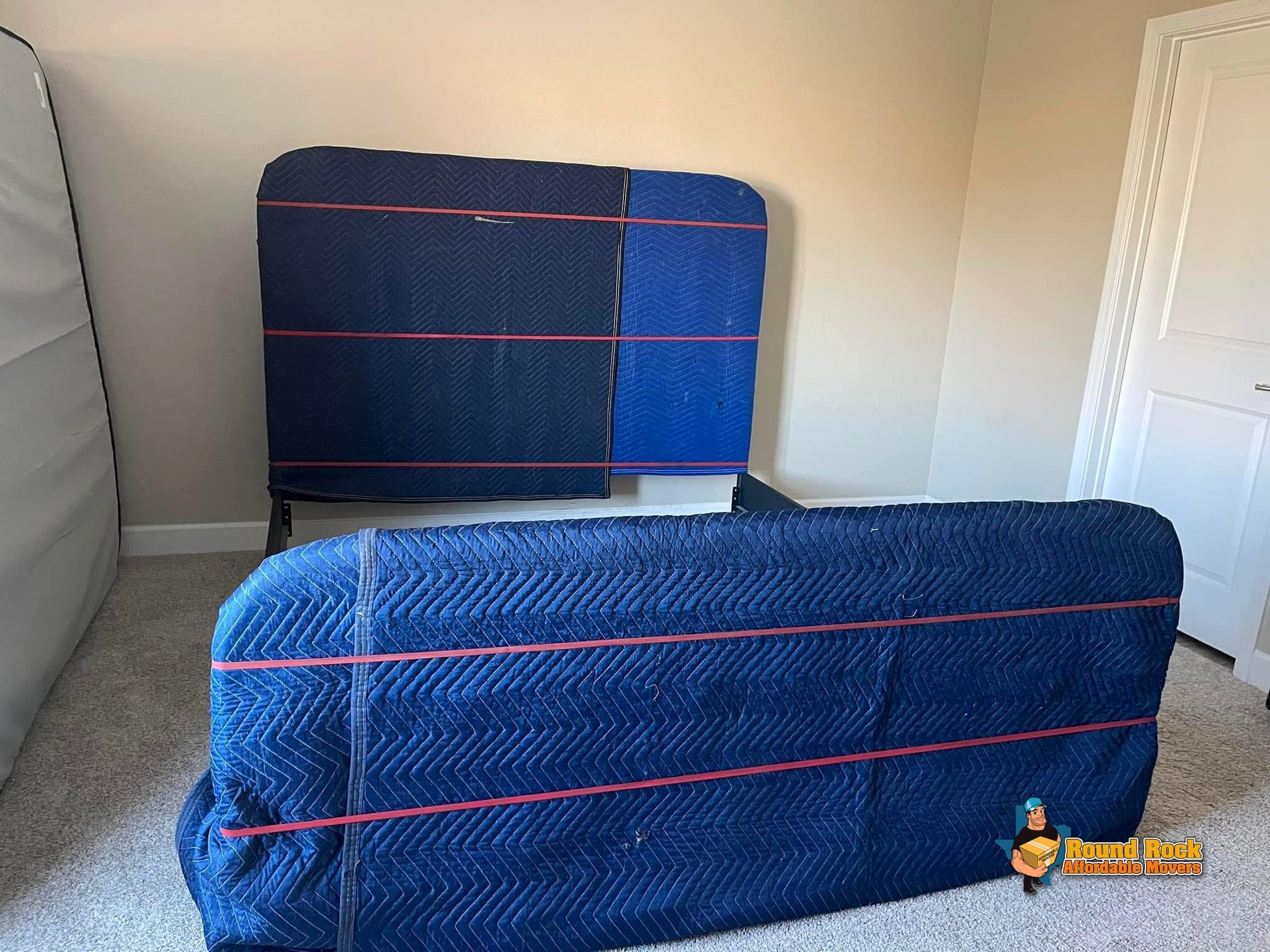 A headboard and bed frame wrapped and secured, by Round Rock Affordable Movers
